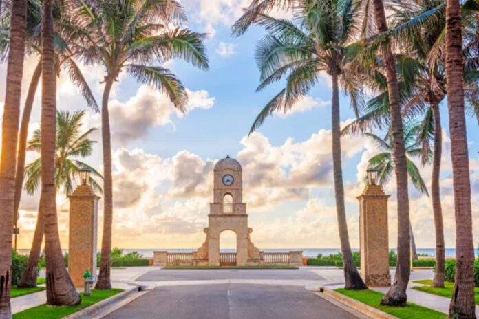 Worth Avenue Clock Tower in Palm Beach surrounded by palm trees, luxury boutiques, and Mediterranean-style architecture on a sunny South Florida day