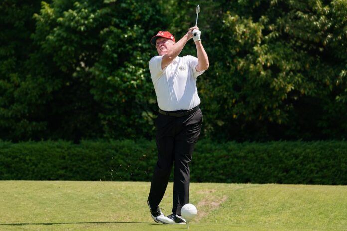 President Donald Trump hits a golf shot during a round of golf.