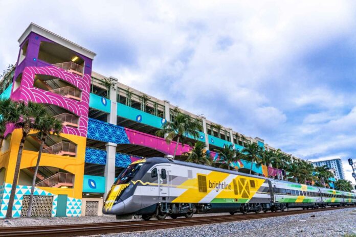 Brightline train beside a colorful building in West Palm Beach, Florida.